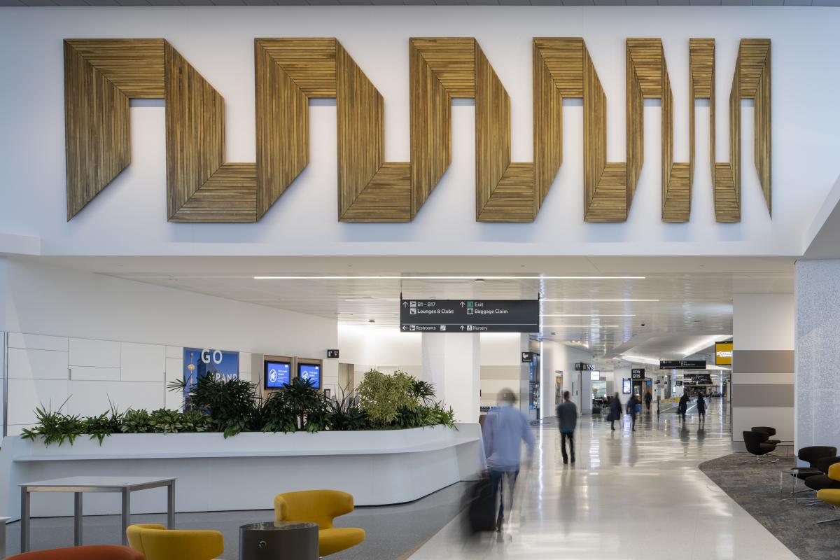 A two-dimensional wall sculpture made of reclaimed lathe and wood. It it installed on a wall that is over a walkway at SFO.