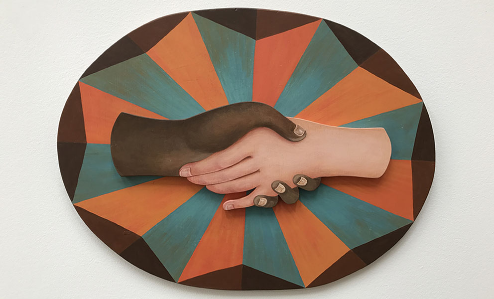 An multi color oval shaped painting of with two different hands clasped in the center