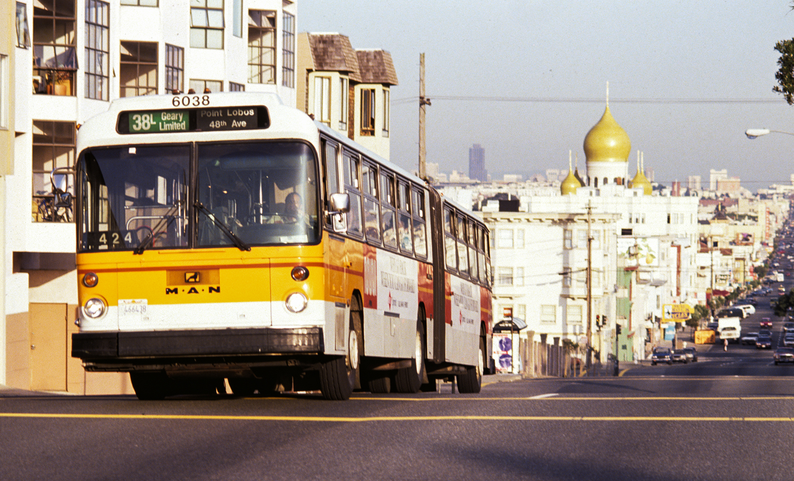 The 38-Geary bus driving down the street with a view of Geary street looking East. 