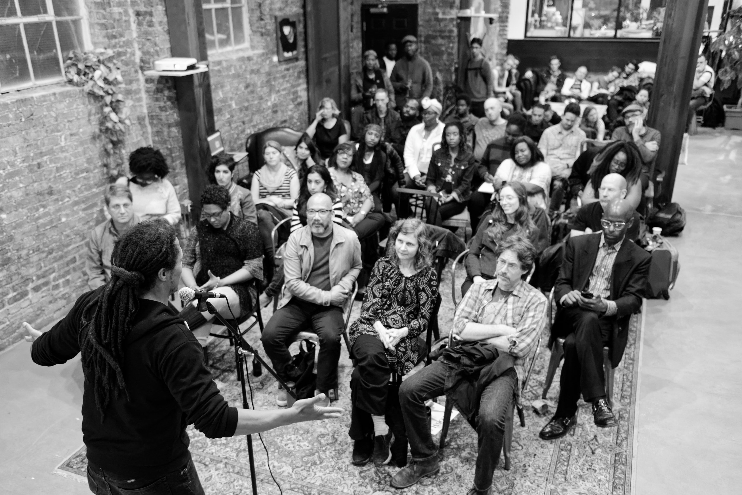 A writer reads in front of an audience. 