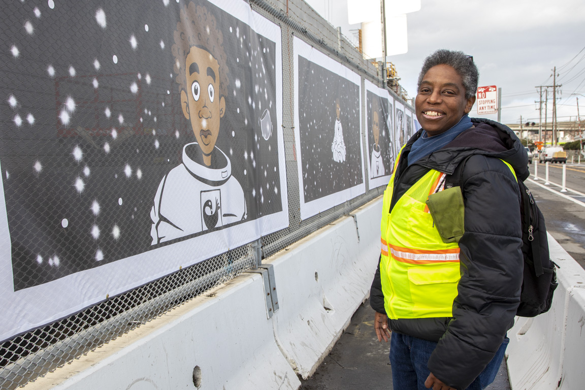 Image of artist standing next to a mural