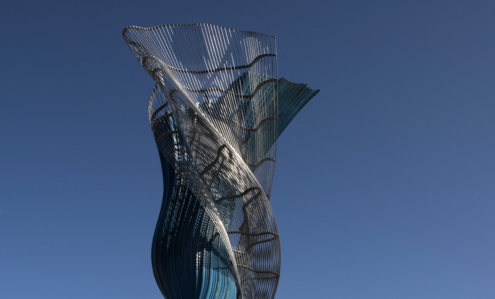 Abstract stainless steel sculpture against a blue sky