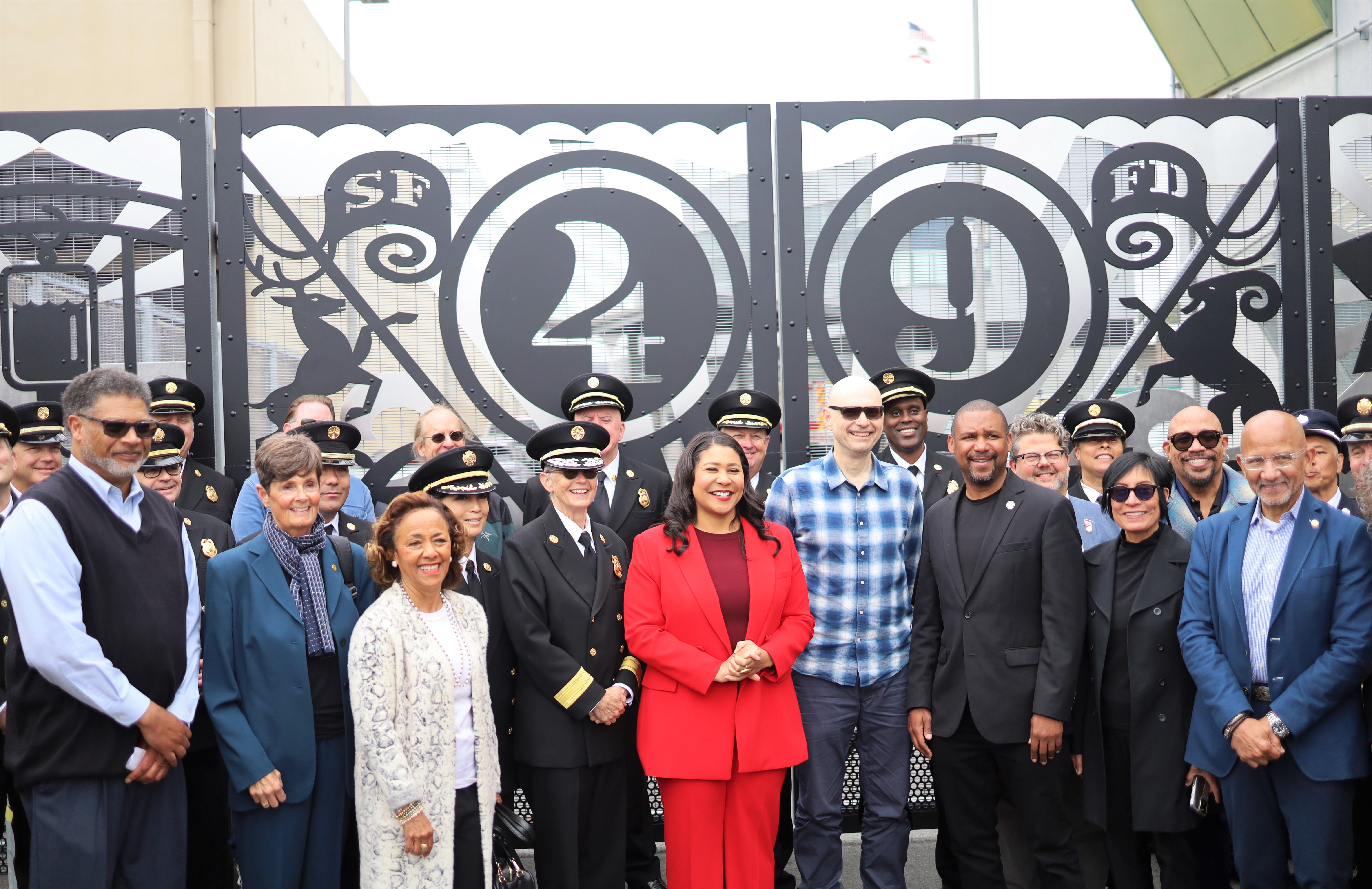 Mayor London Breed with group of City Officials and special guests standing in front of the fence of Station 49