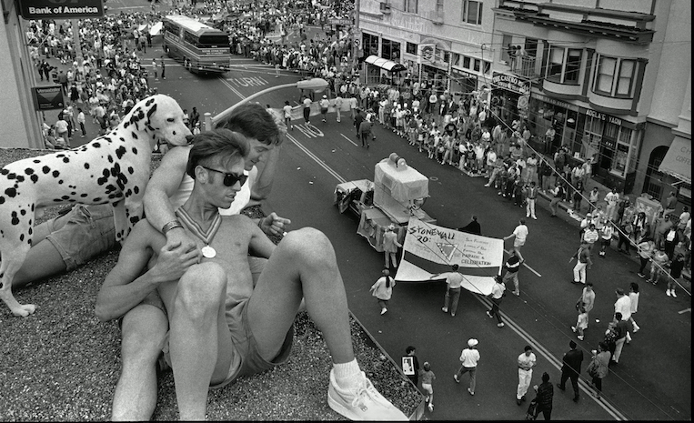 Black and white image of two men on the rooftop of a building during the Pride parade
