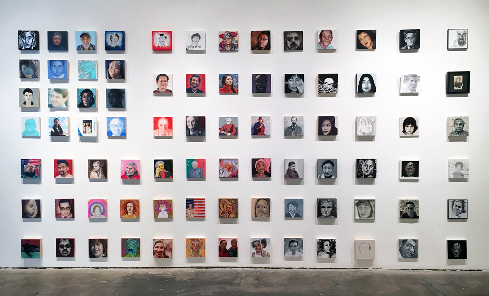 White wall with individual portraits hanging in the formation of a flag.