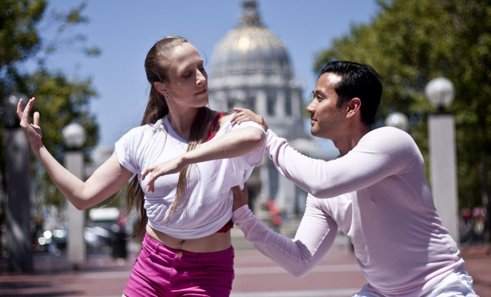 Two dancers dressed in pink and white dancing in front of City Hall